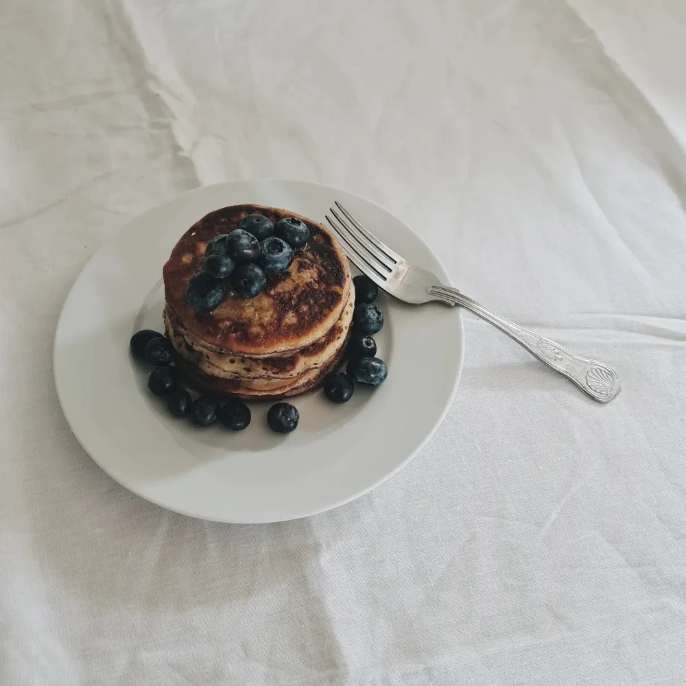banana + sourdough pancakes served on a white plate with blueberries and a silver fork