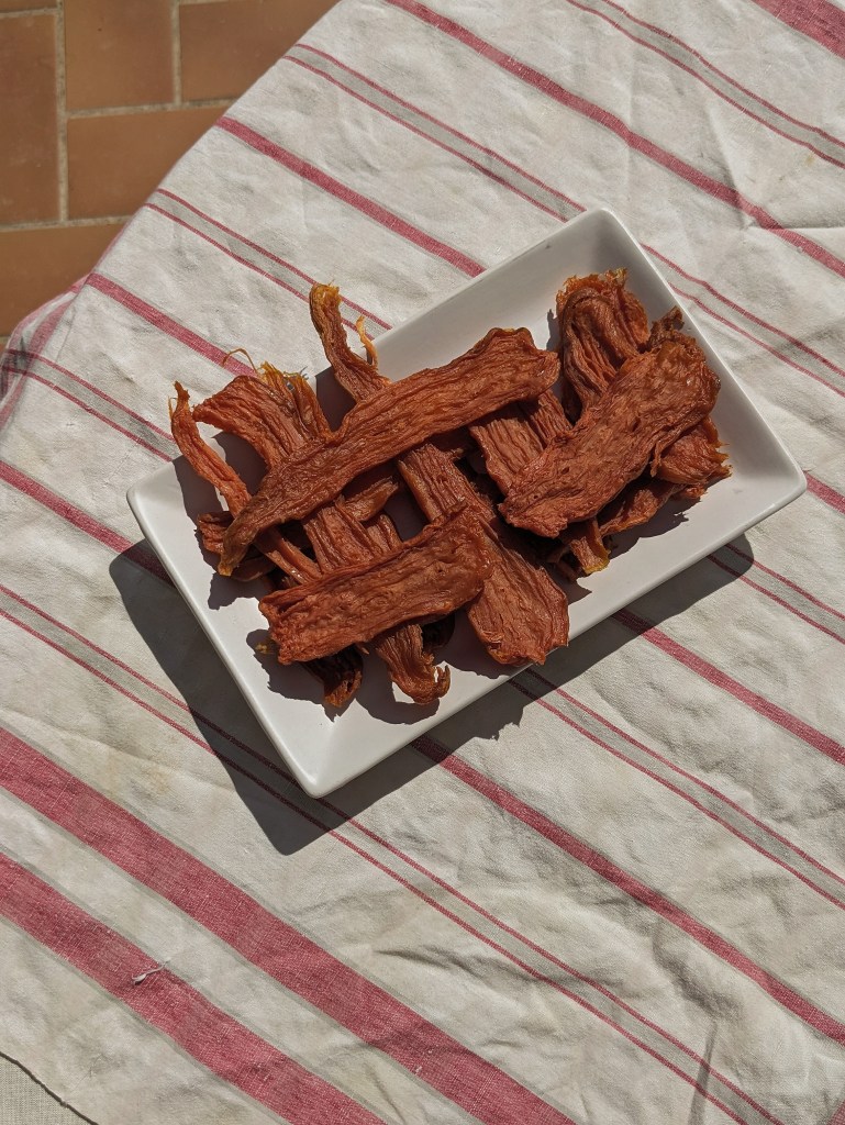 a serving of sun dried sweet on a square plate placed on a striped tablecloth
